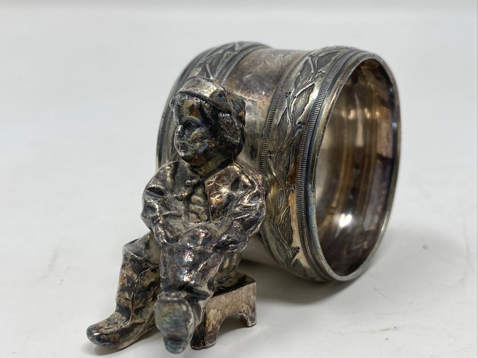 This is authentic. It is unmarked. It has a boy sitting on a stool in front of the ring.